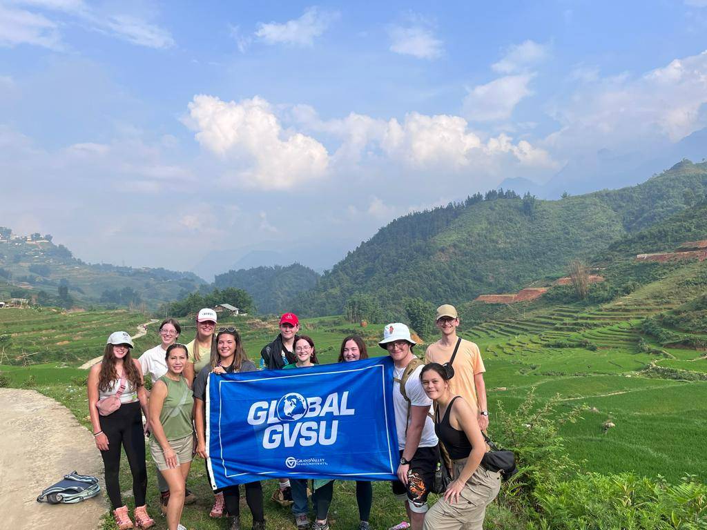 study abroad students standing outside with GVSU Global flag